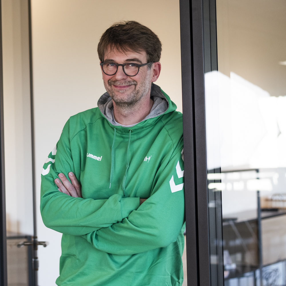 Oliver Ziehm, freundlich lächelnd, mit verschränkten Armen an einem Türrahmen lehnend